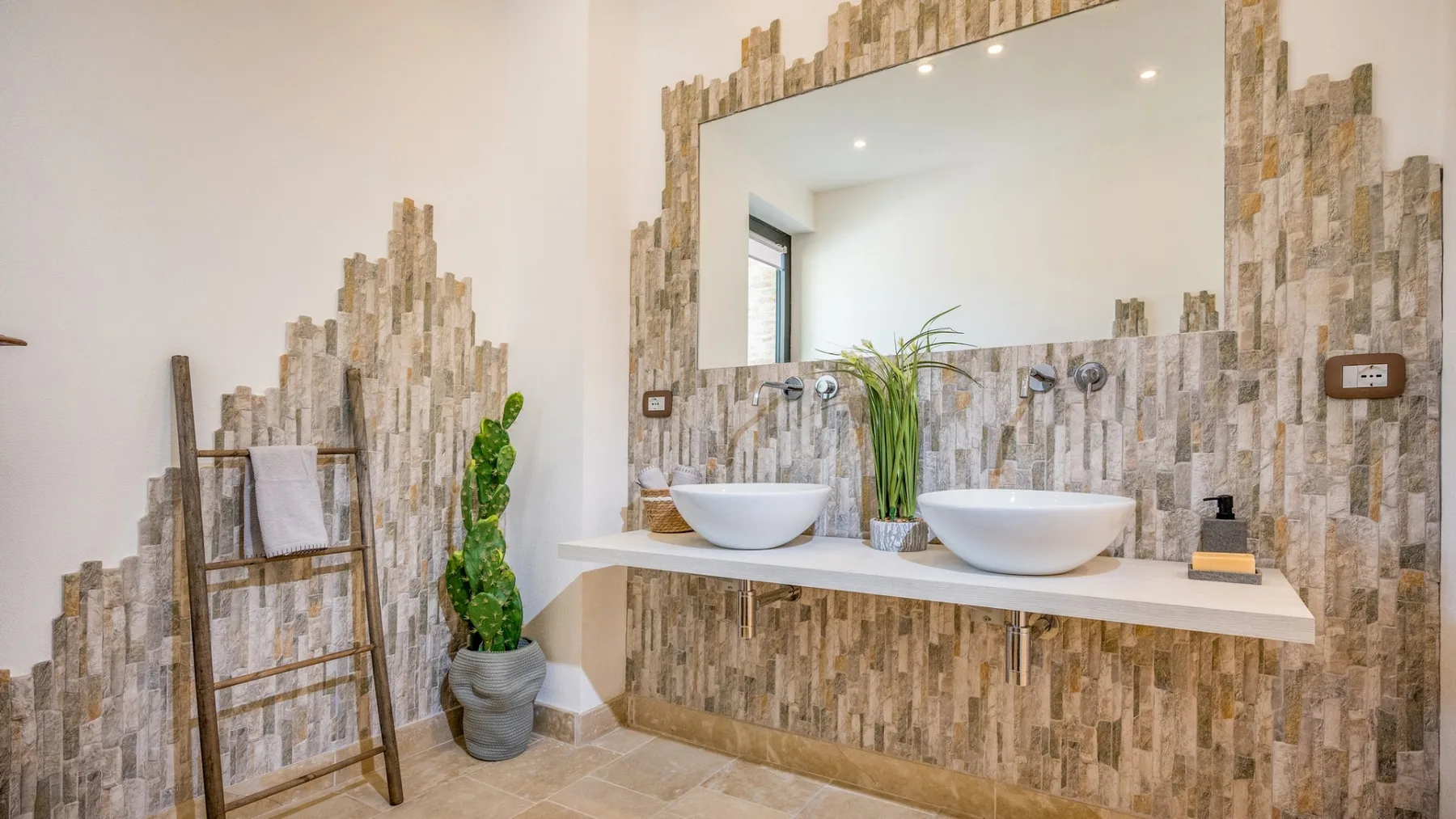 Un tocador de baño tiene dos lavabos sobre la encimera y un gran espejo.