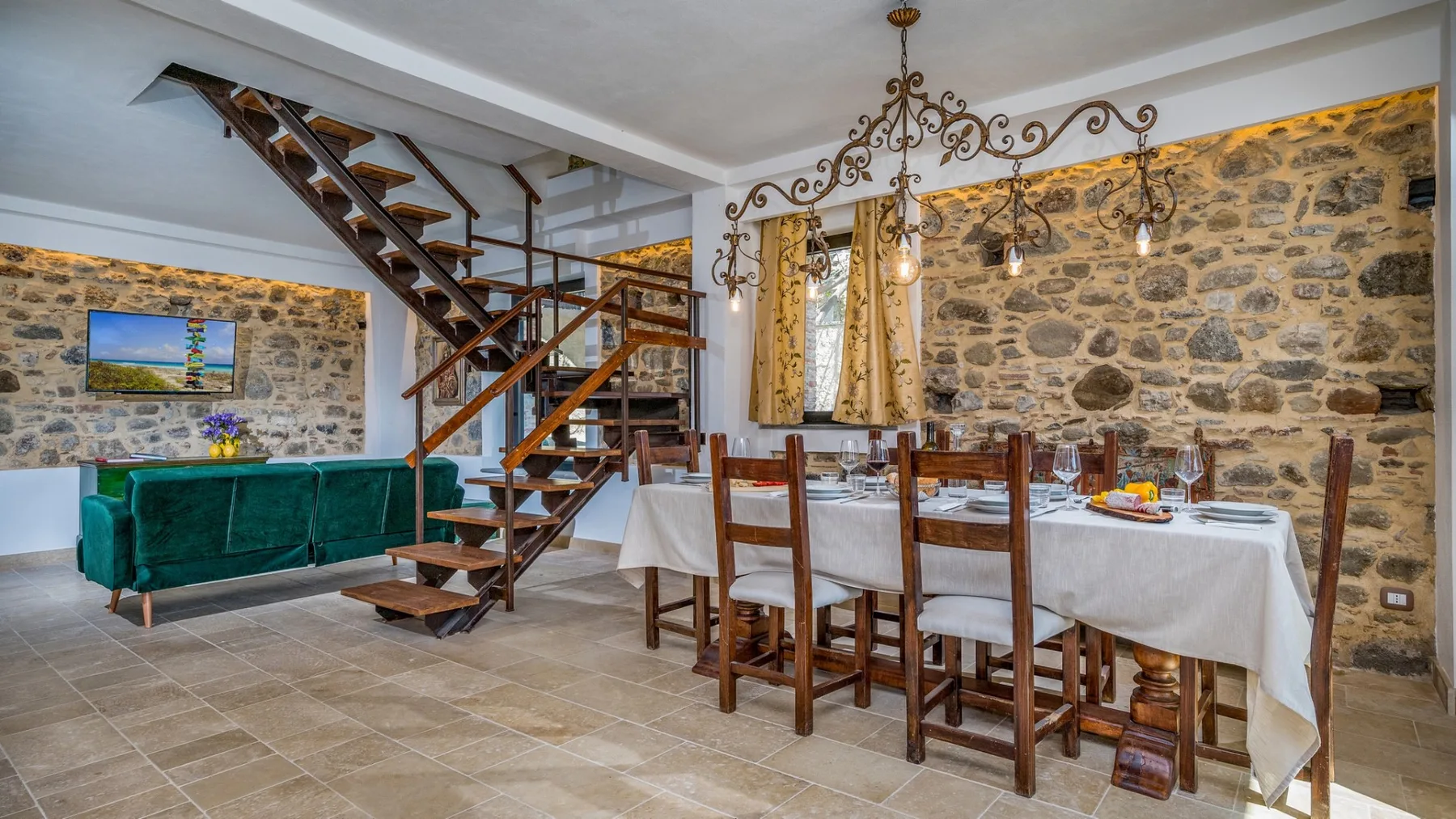 Un comedor rústico con una mesa larga junto a una escalera de madera abierta.