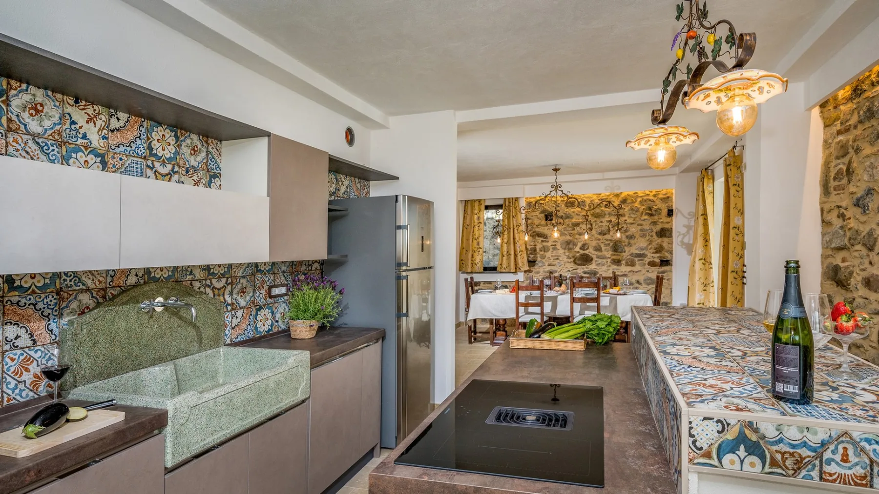 Una cocina con azulejos, una placa de cocina central, una encimera y una mesa al fondo.