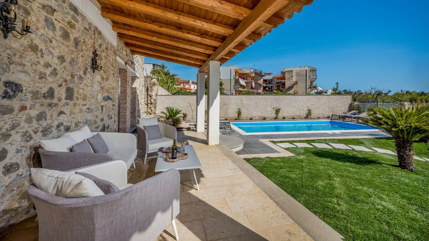 Un patio cubierto da a una piscina y un césped.