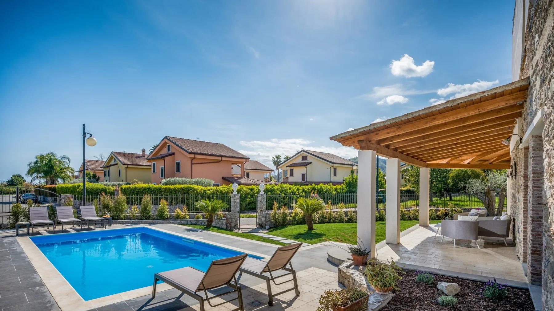 Una piscina y un patio con asientos al aire libre junto a una terraza cubierta.