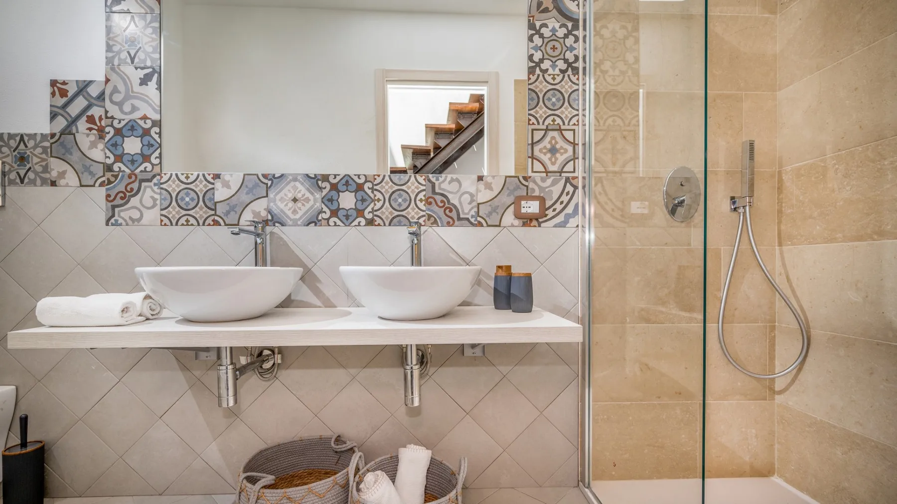 Un baño alicatado con dos lavabos y una ducha con panel de vidrio.