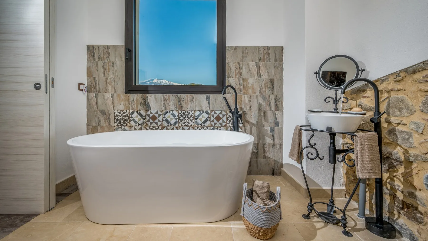 Un baño con una bañera exenta, un lavabo y paredes revestidas de azulejos.