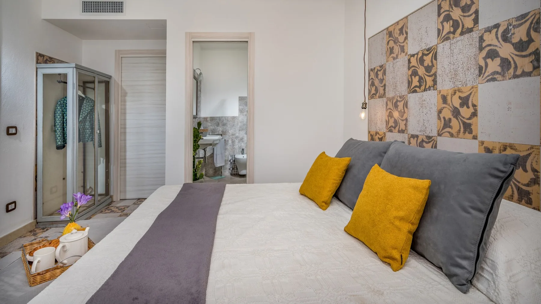 Un dormitorio con una cama bien tendida y almohadas de color mostaza.