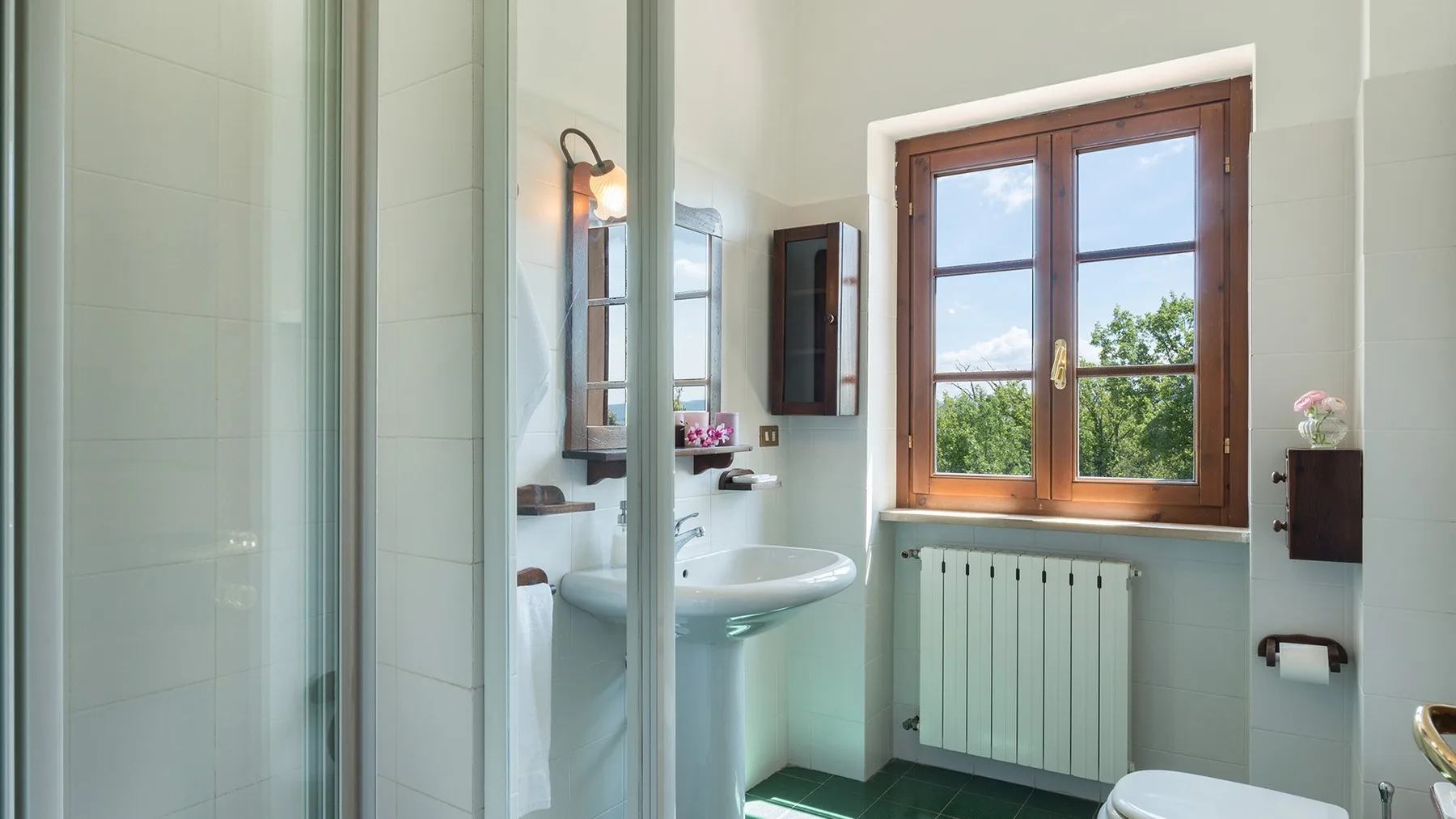 Un baño con lavabo de pedestal, ventana y radiador.