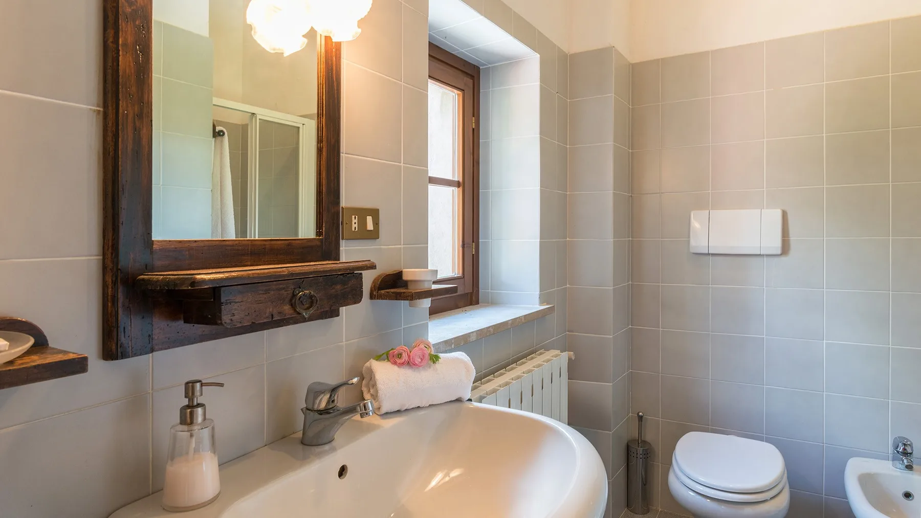 Un baño con azulejos, lavabo, inodoro y una ventana.