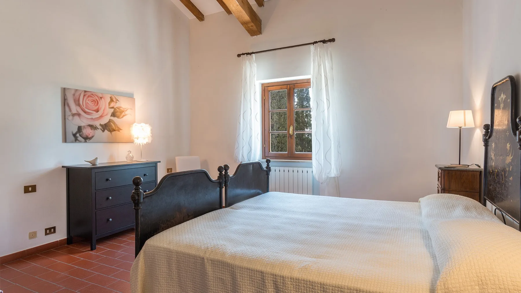 Un dormitorio con una cama grande, una cómoda y una ventana con cortinas.