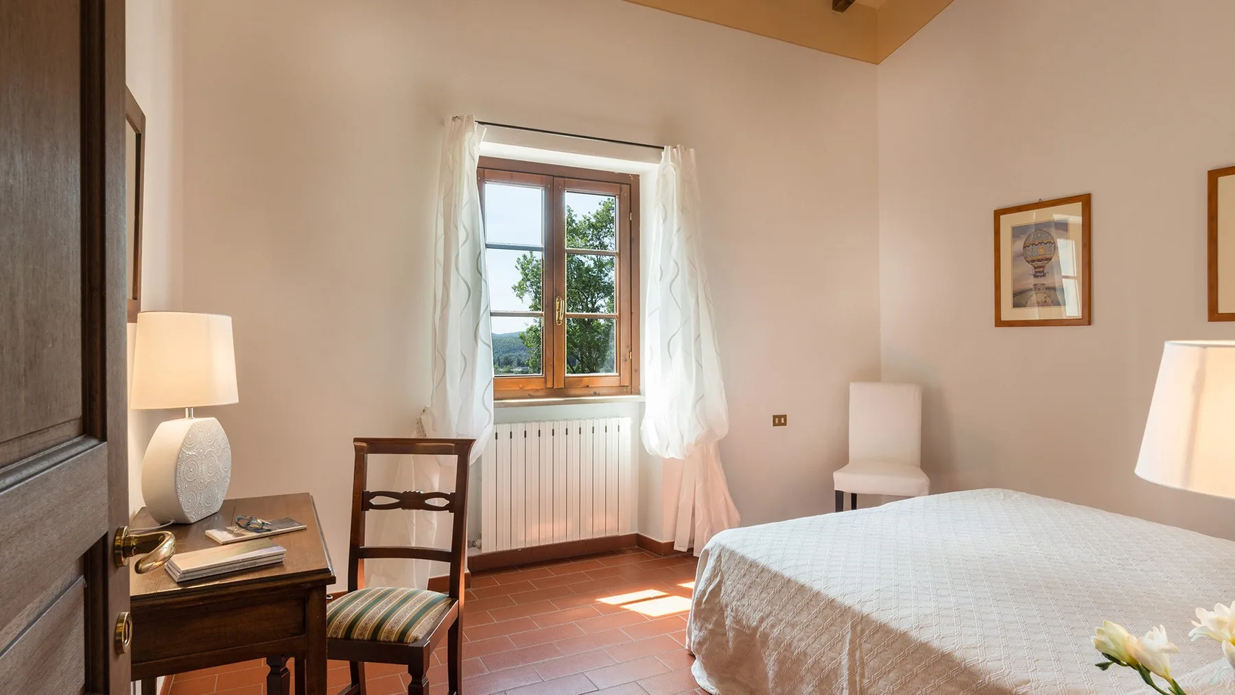 Un dormitorio con una cama, una ventana y un pequeño escritorio.