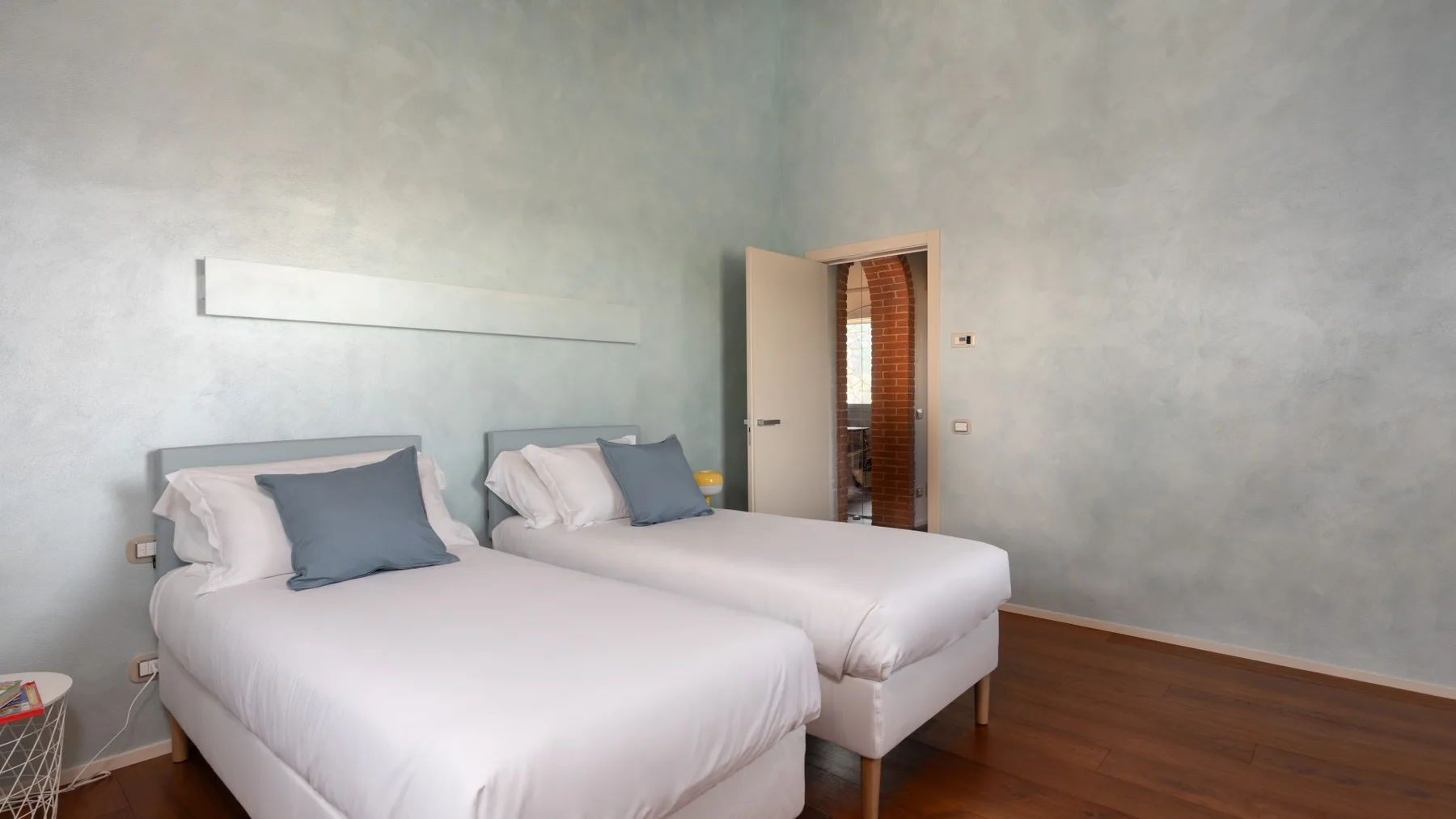 A bedroom with two beds and a doorway opening to another room.
