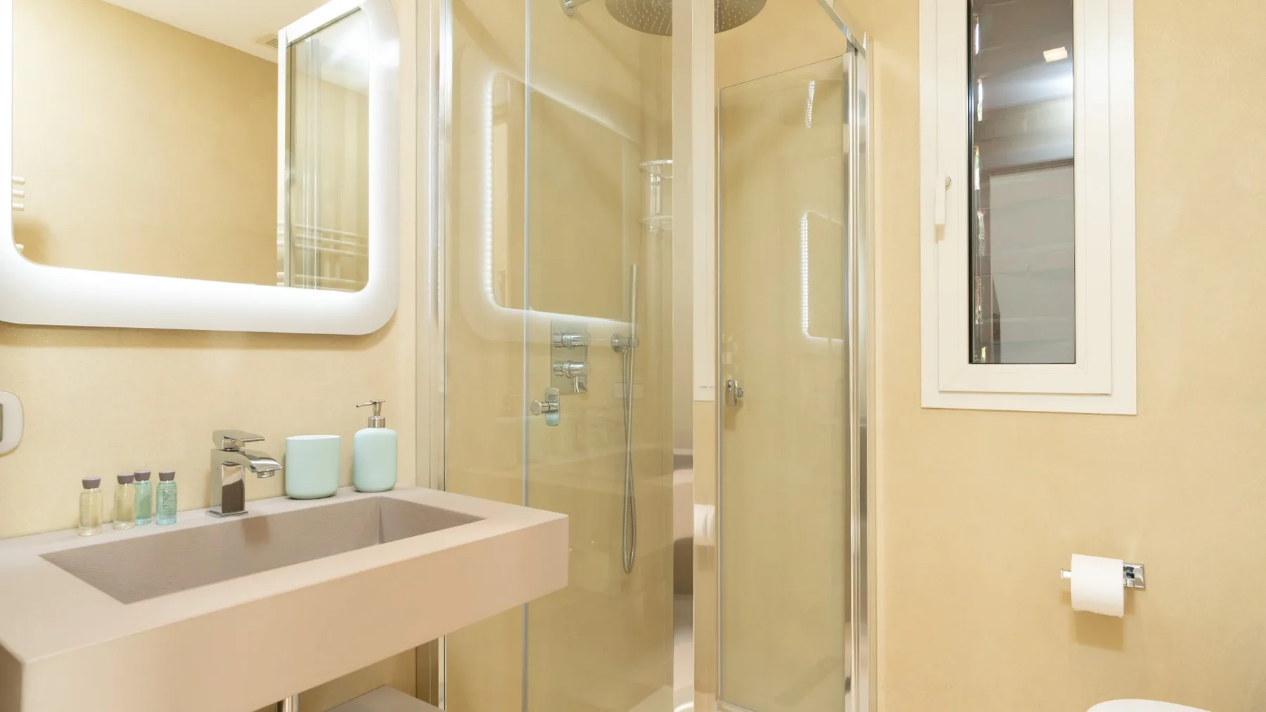 A bright bathroom with a sink, wall mirror, and glass shower.
