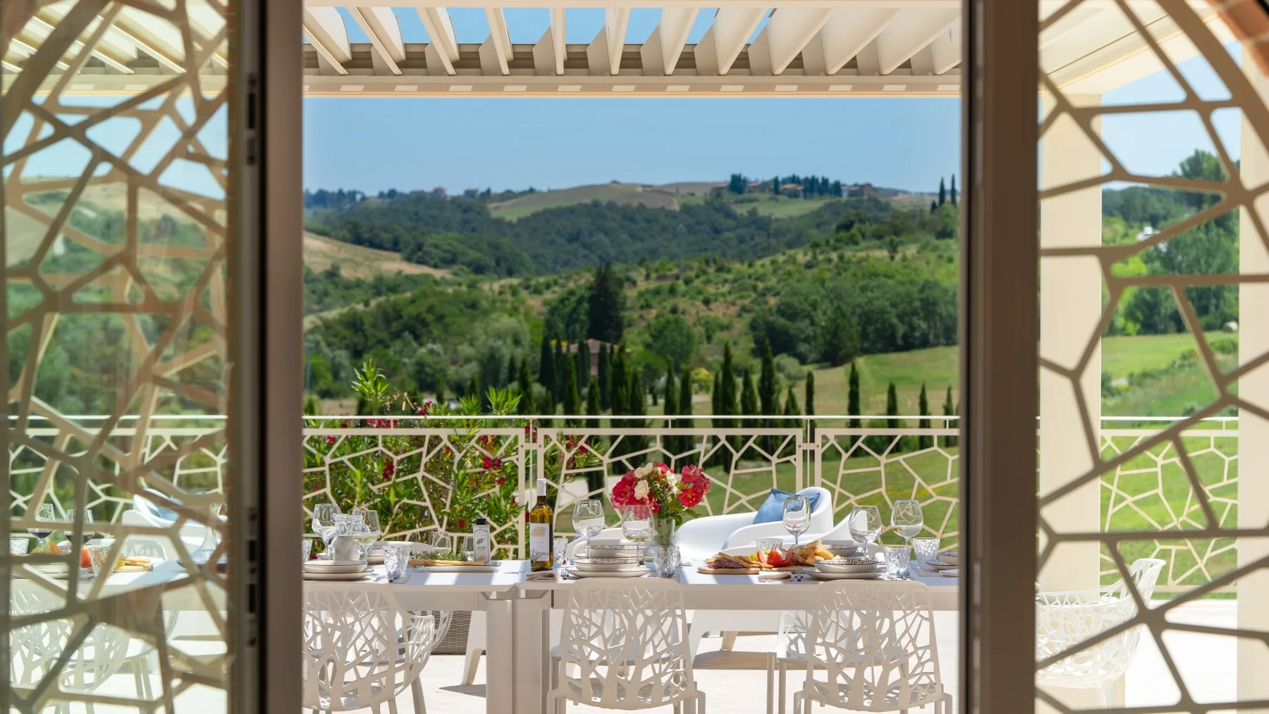 A dining terrace with a set table overlooking green hills.