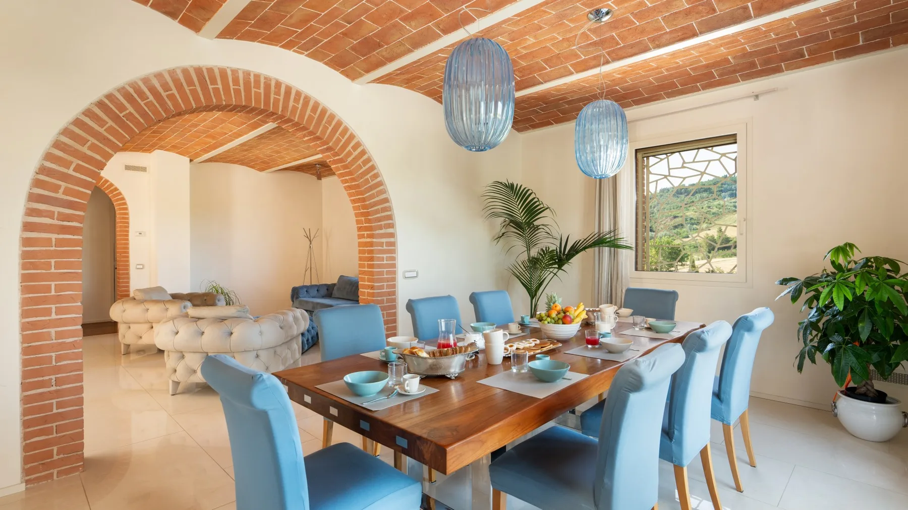 A dining area with a wooden table and blue seating beneath a brick ceiling.