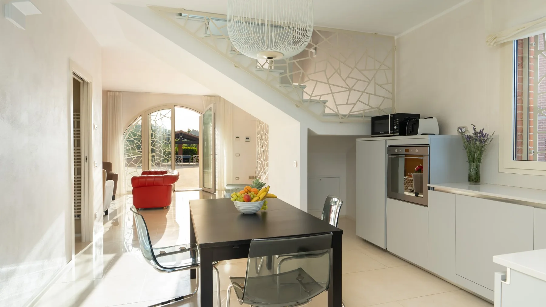 A bright dining area with a dark table beside a modern kitchen.