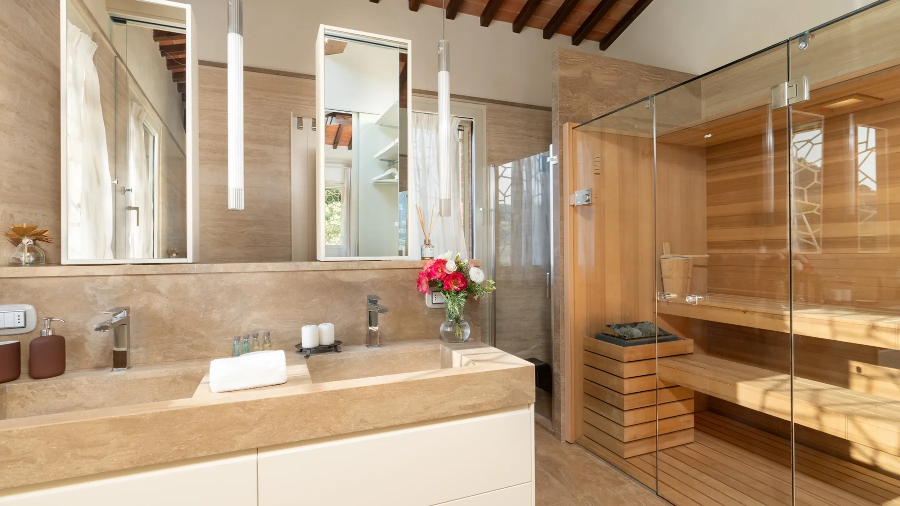 A bathroom with a long stone vanity, mirrors, and a glass-enclosed shower.