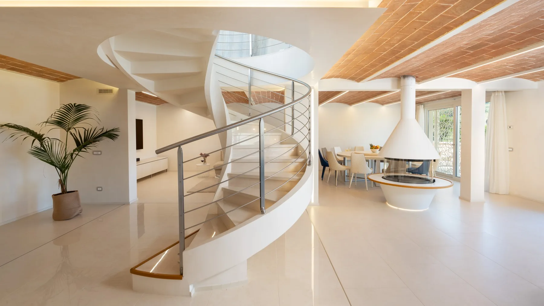 A bright open-plan living area with a curved staircase and dining space.