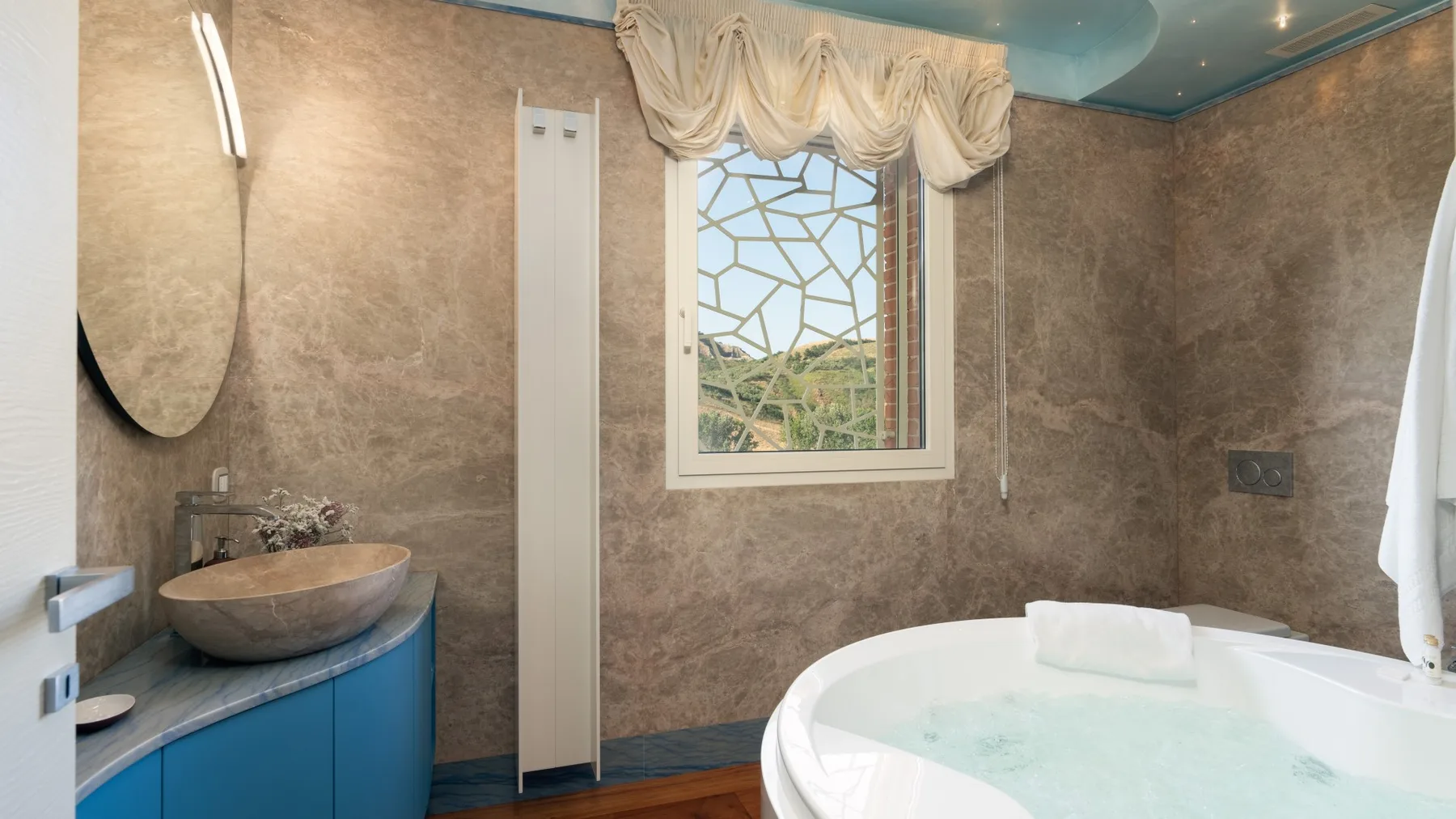 A bathroom with a large bathtub and a window overlooking greenery.