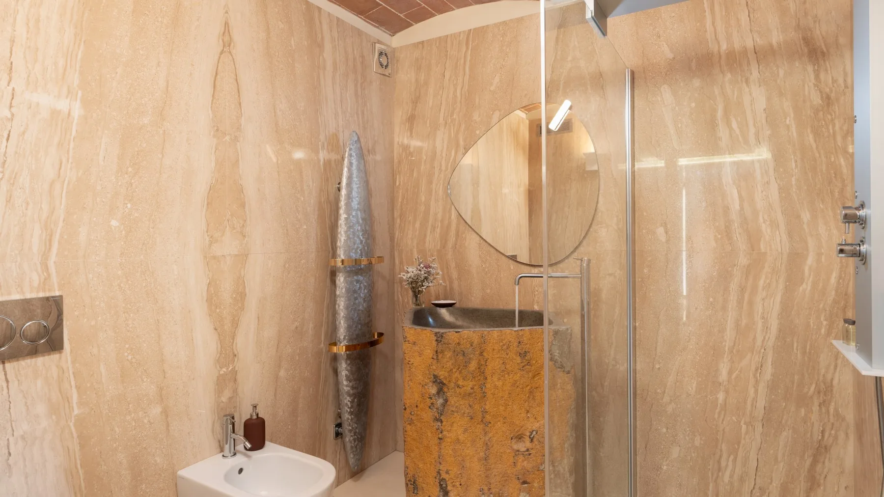 A bathroom with a vessel sink, wall mirror, and glass shower screen.