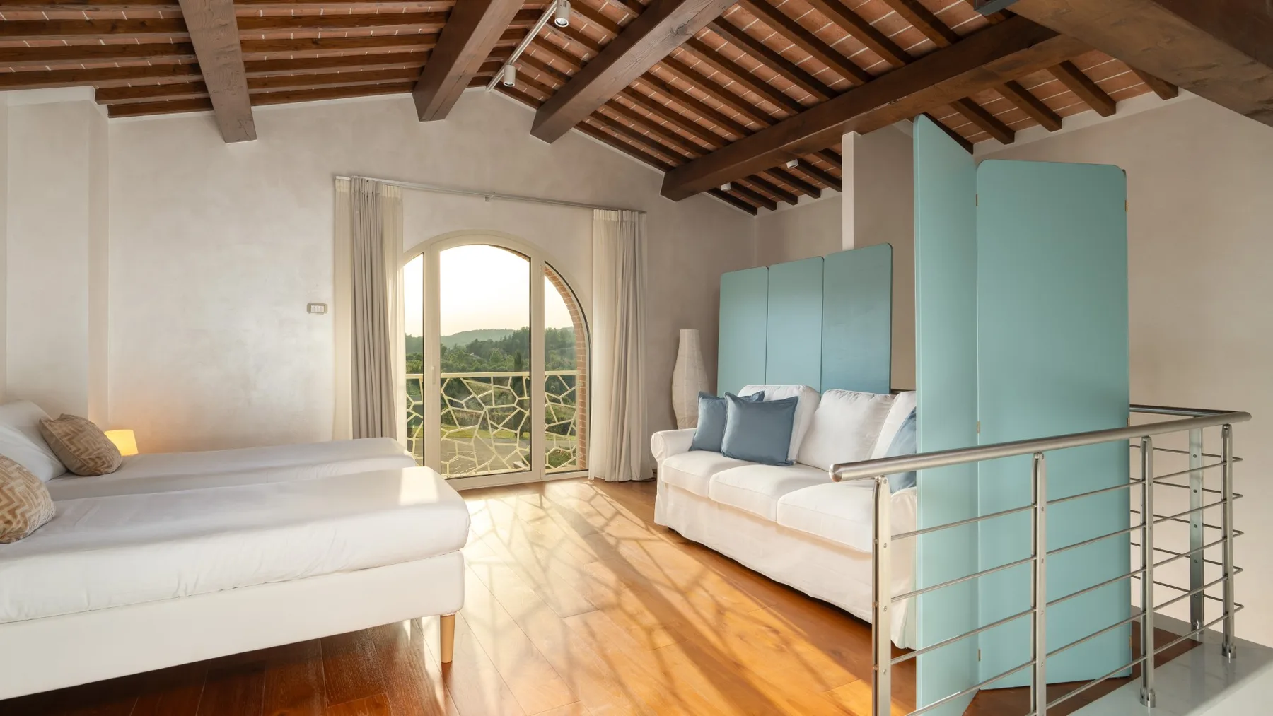 A bright bedroom with a bed, a sofa, and glass doors opening to a balcony.