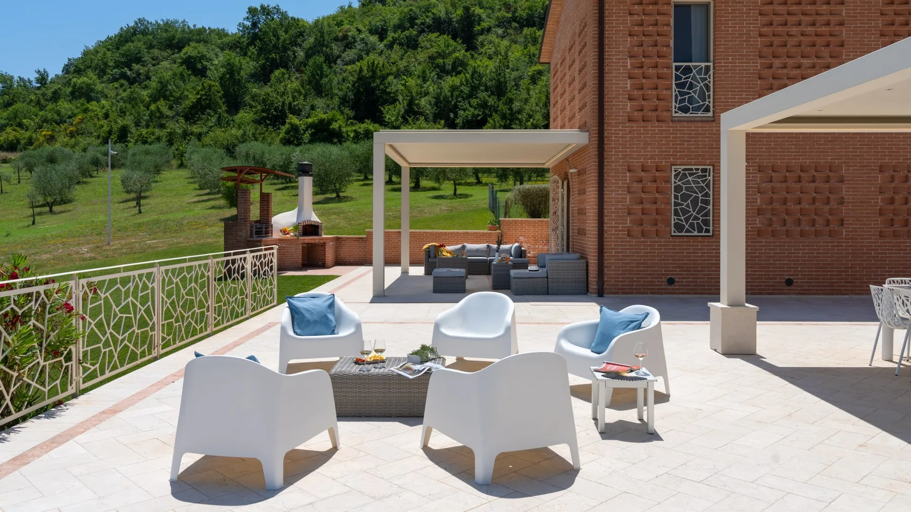 An outdoor patio with seating and a shaded lounge area beside a brick building.