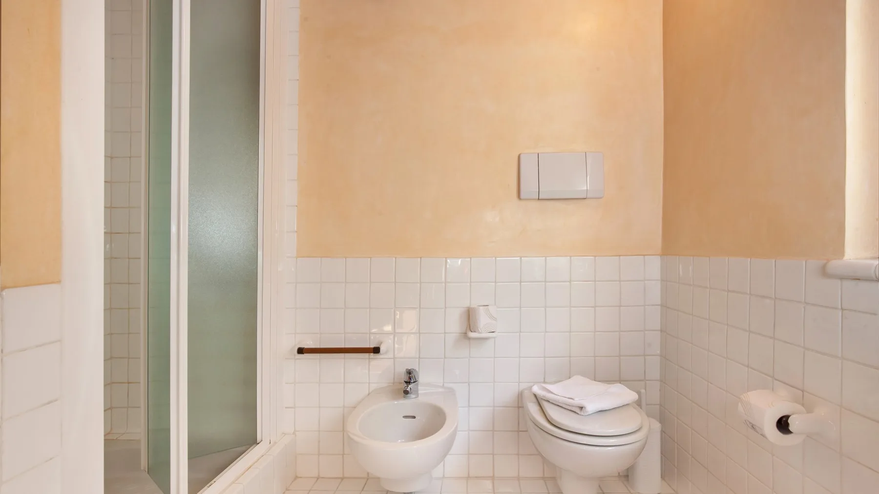 A tiled bathroom with a shower, bidet, and toilet.