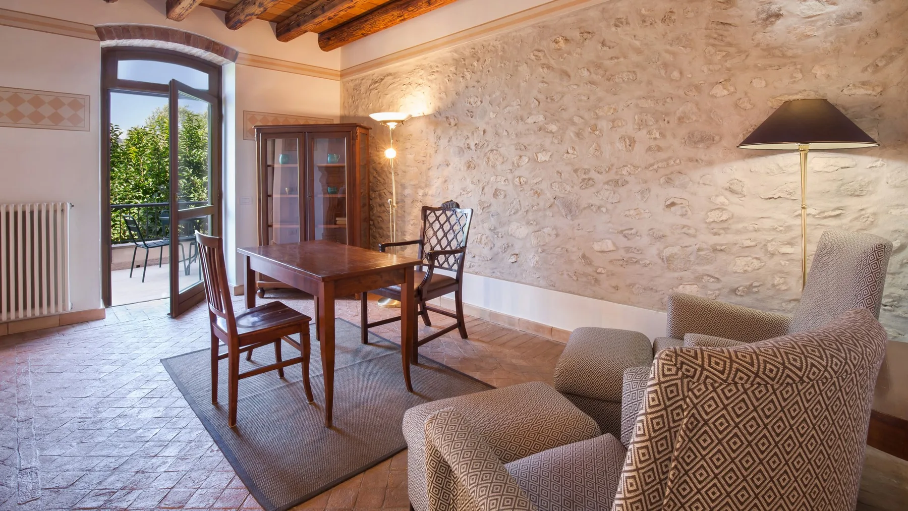 A dining and sitting room with a wooden table and upholstered seating.