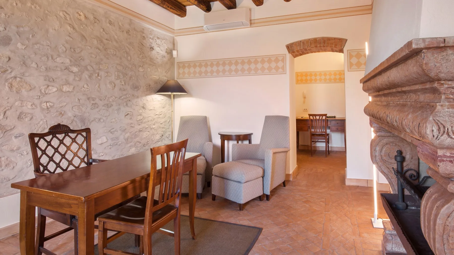 A rustic sitting room with a wooden dining table and upholstered seating.