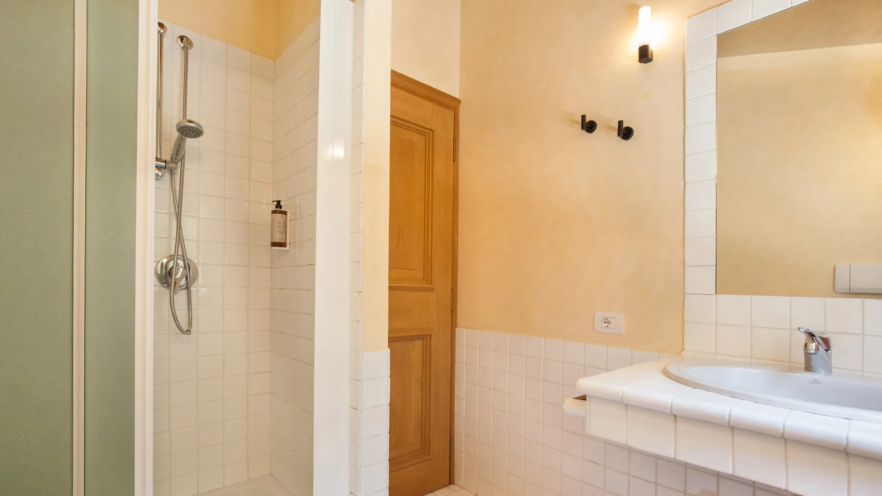 A tiled bathroom with a glass shower enclosure and a sink.