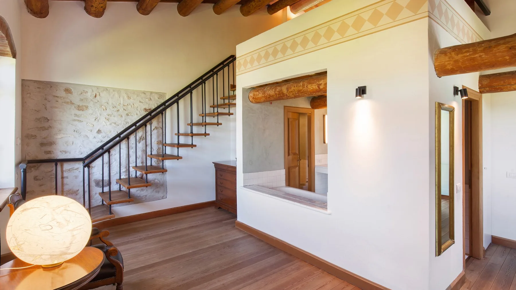 An interior room with a wooden staircase and a wide opening in the wall.