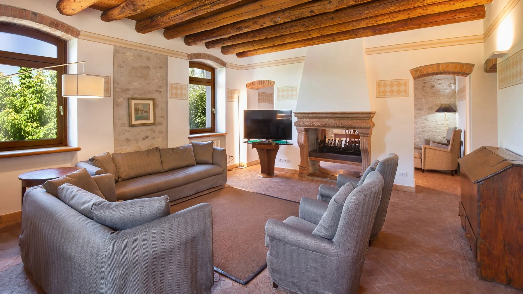 A living room with upholstered seating, a television, and a fireplace.