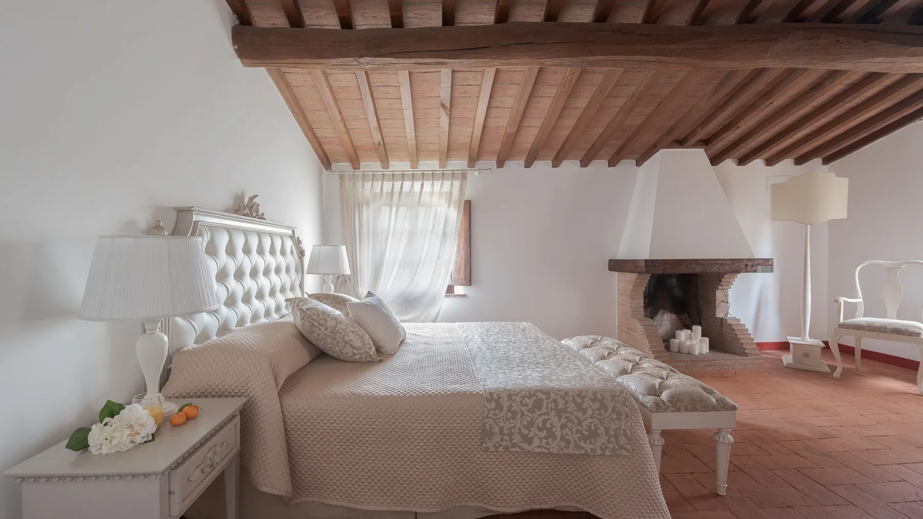 Un dormitorio con una cama grande, una ventana con cortinas y una chimenea.
