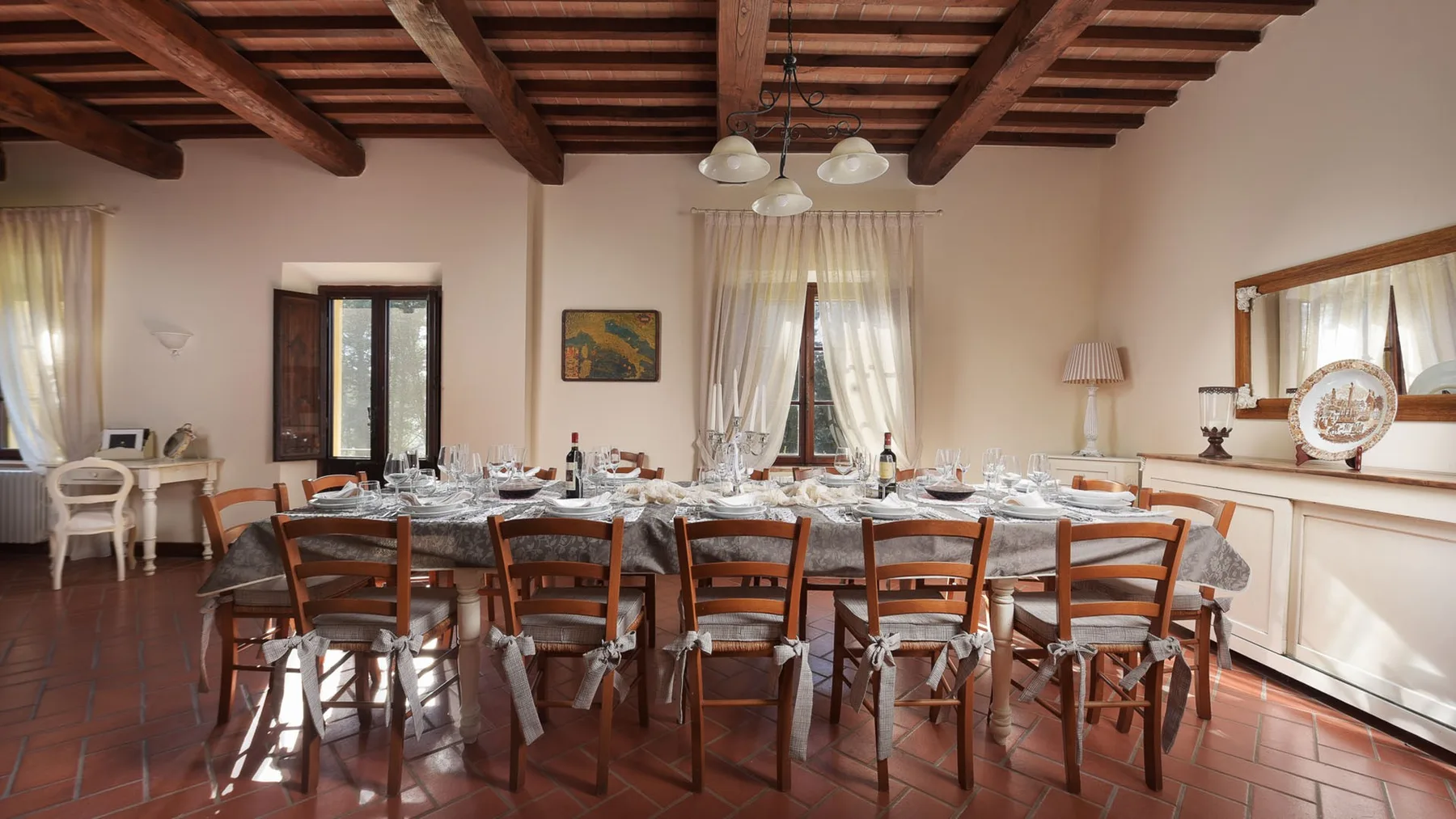 Un comedor con una mesa larga puesta con platos y sillas alrededor.