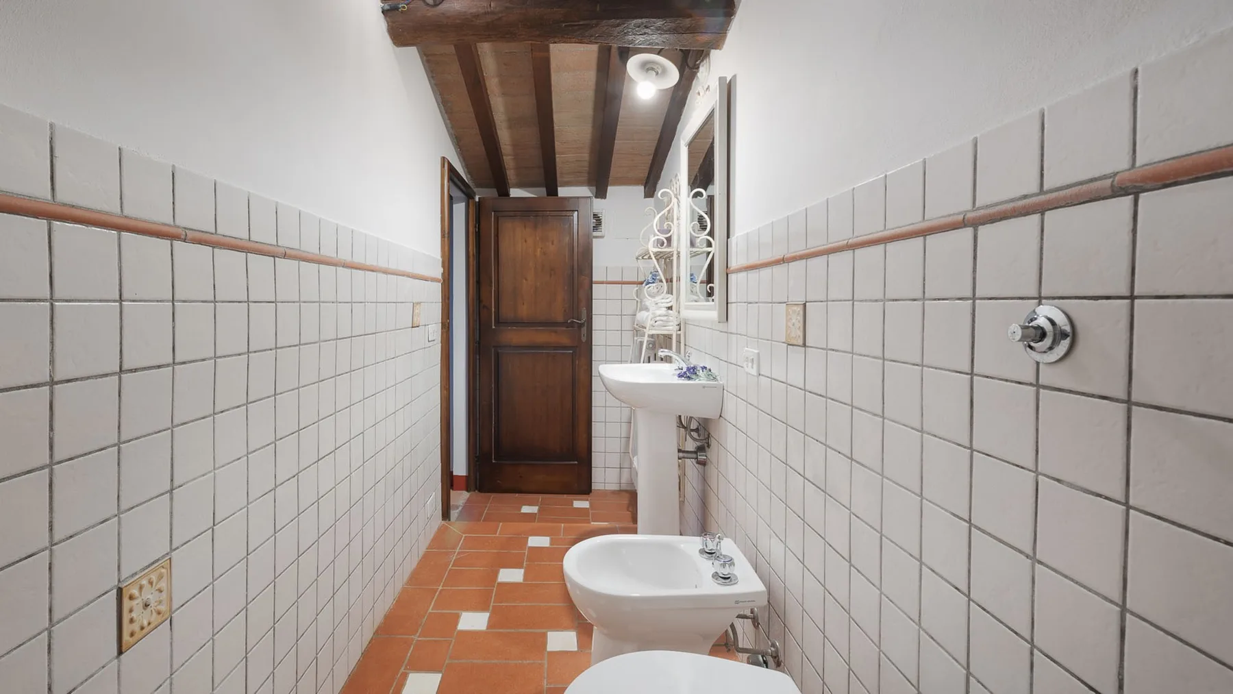 Un baño estrecho con azulejos, lavabo y bidé.