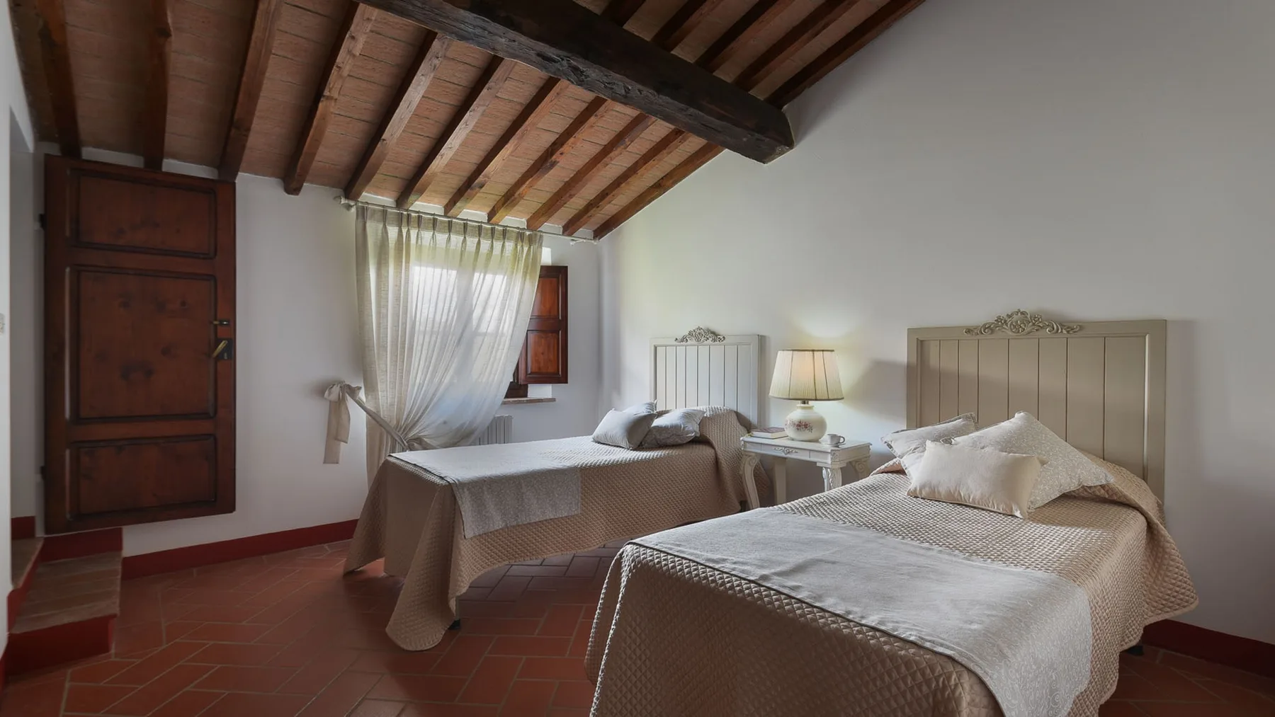 Un dormitorio con dos camas, ropa de cama blanca y vigas de madera a la vista.