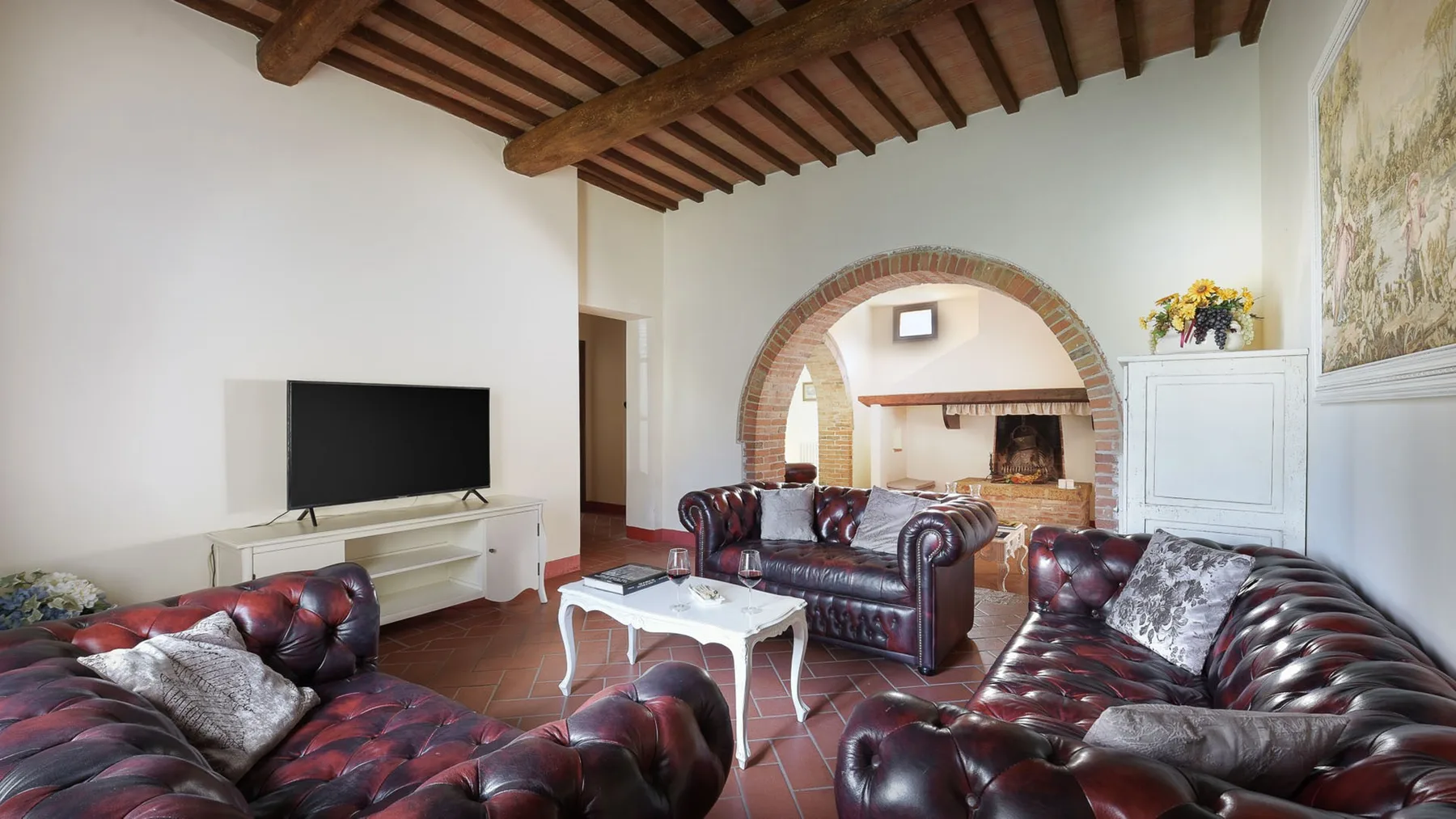 Una sala de estar con asientos de cuero, una mesa de centro y una chimenea con arco.