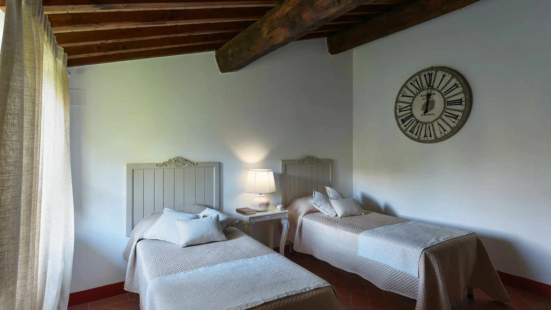 Un dormitorio con dos camas, mesillas de noche y vigas de madera a la vista.