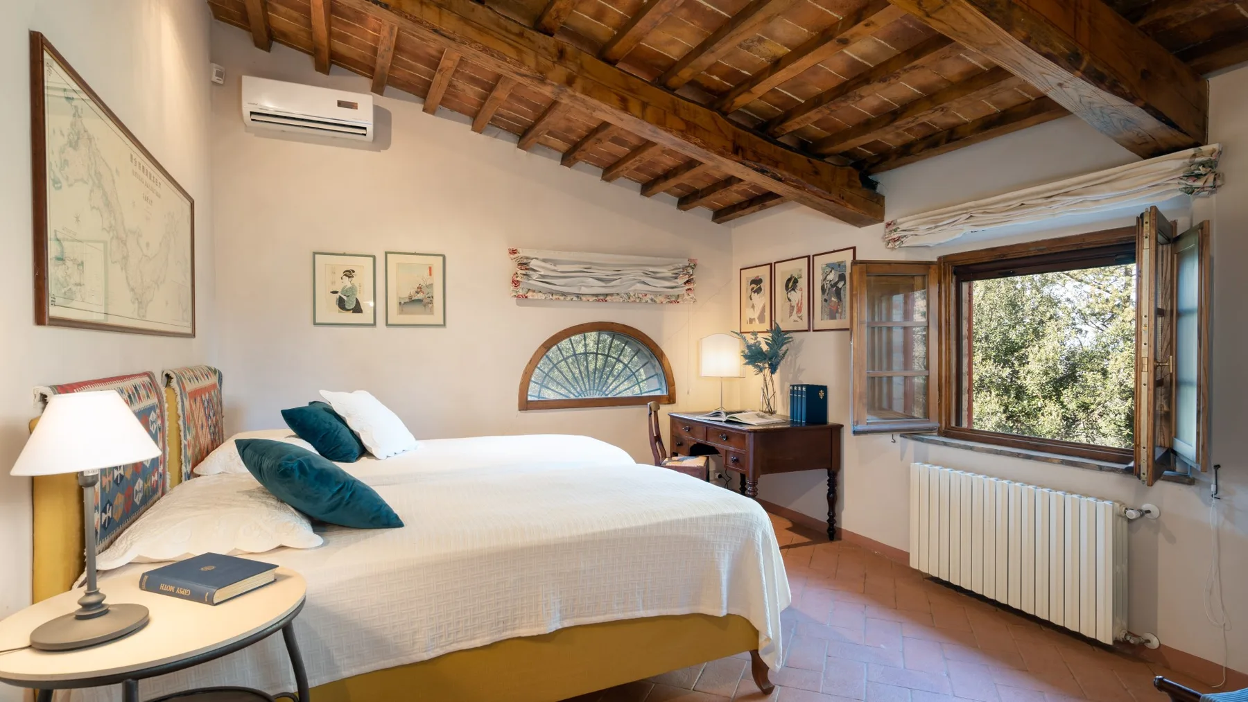 A bedroom with a bed, bedside tables, and an open window beneath a wooden ceiling.