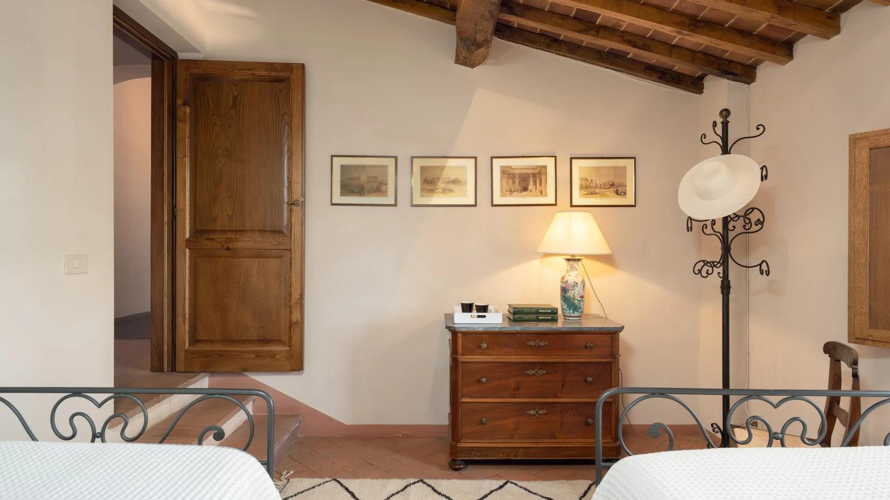 A bedroom with wooden furniture, framed pictures, and exposed ceiling beams.