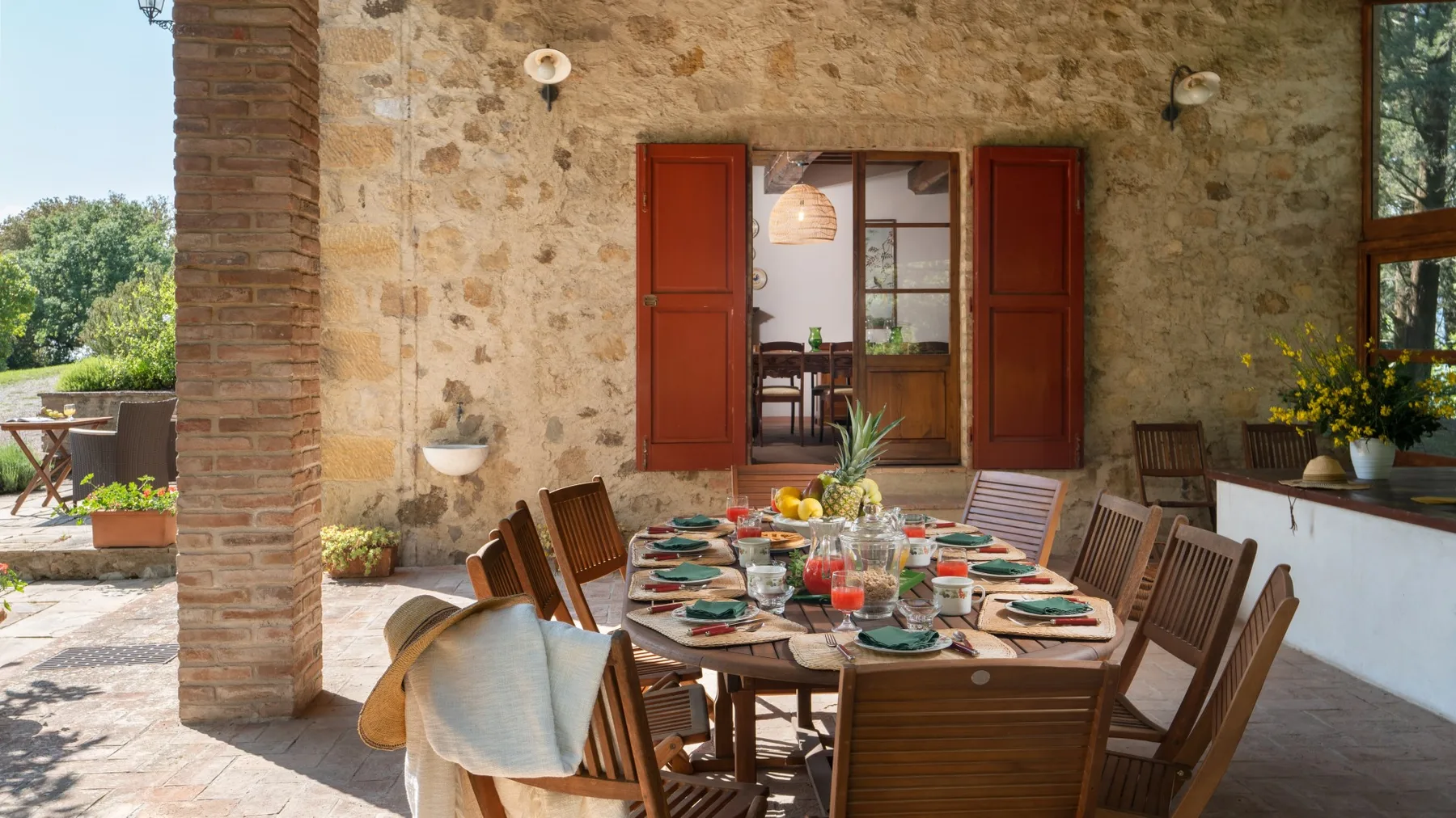 A rustic dining room with a long table set with colorful dishes and surrounded by wooden seating.