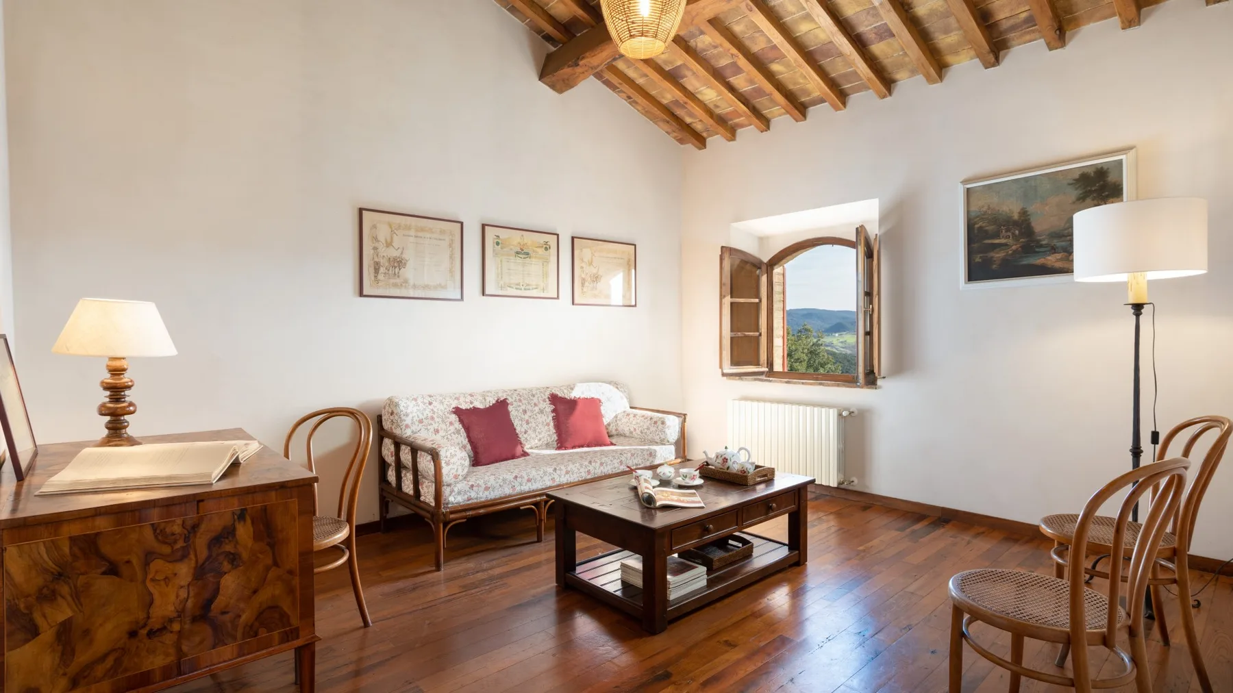 A living room with a patterned sofa, wooden coffee table, and exposed ceiling beams.