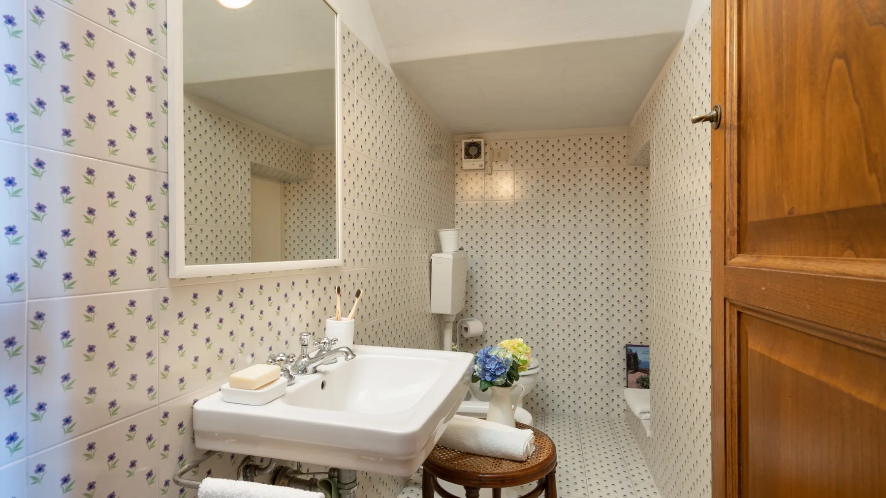 A tiled bathroom with a sink, mirror, and shower area.