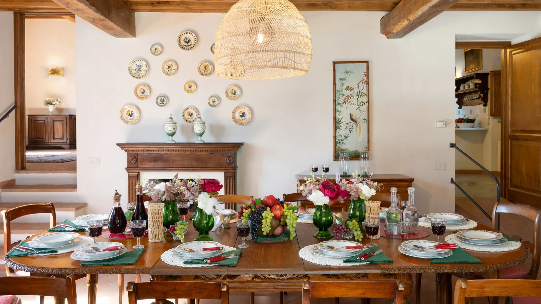 A dining room with a long wooden table set with dishes and flowers.