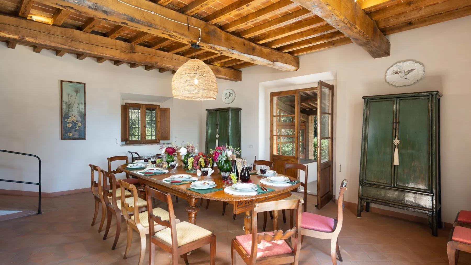 A dining room with a long wooden table set with dishes and flowers.