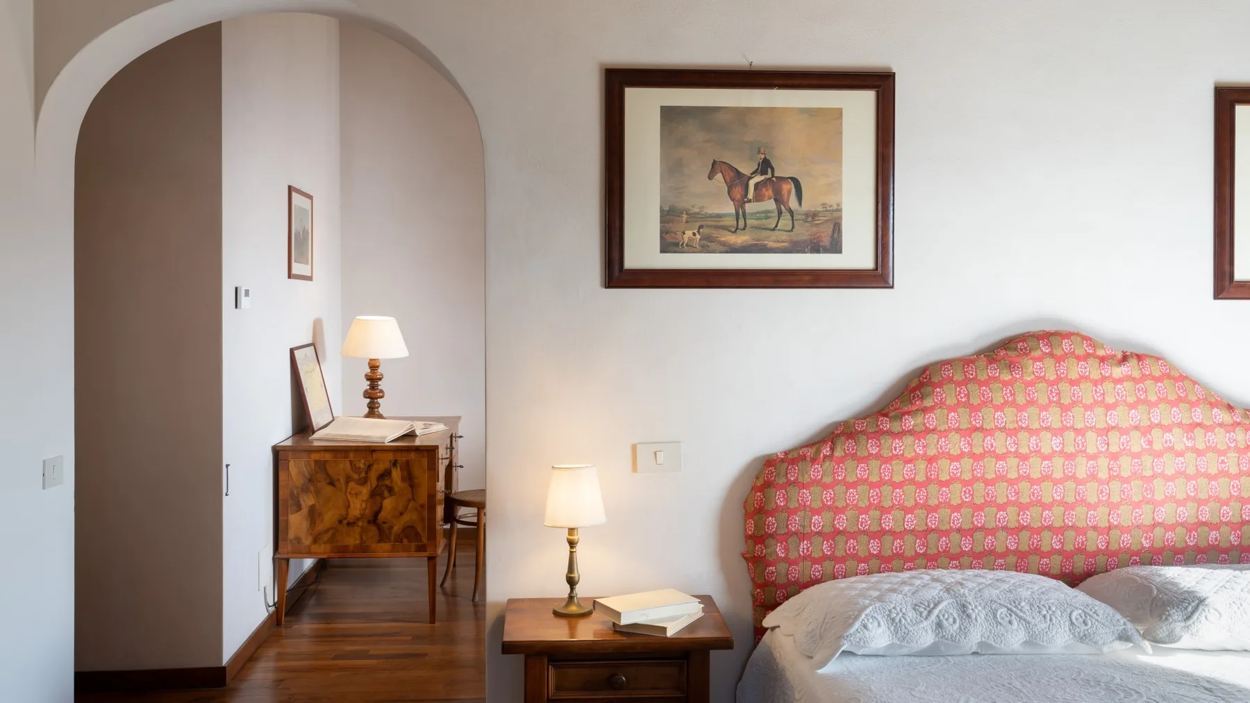 A bedroom with a patterned bed and a small wooden table beside it.