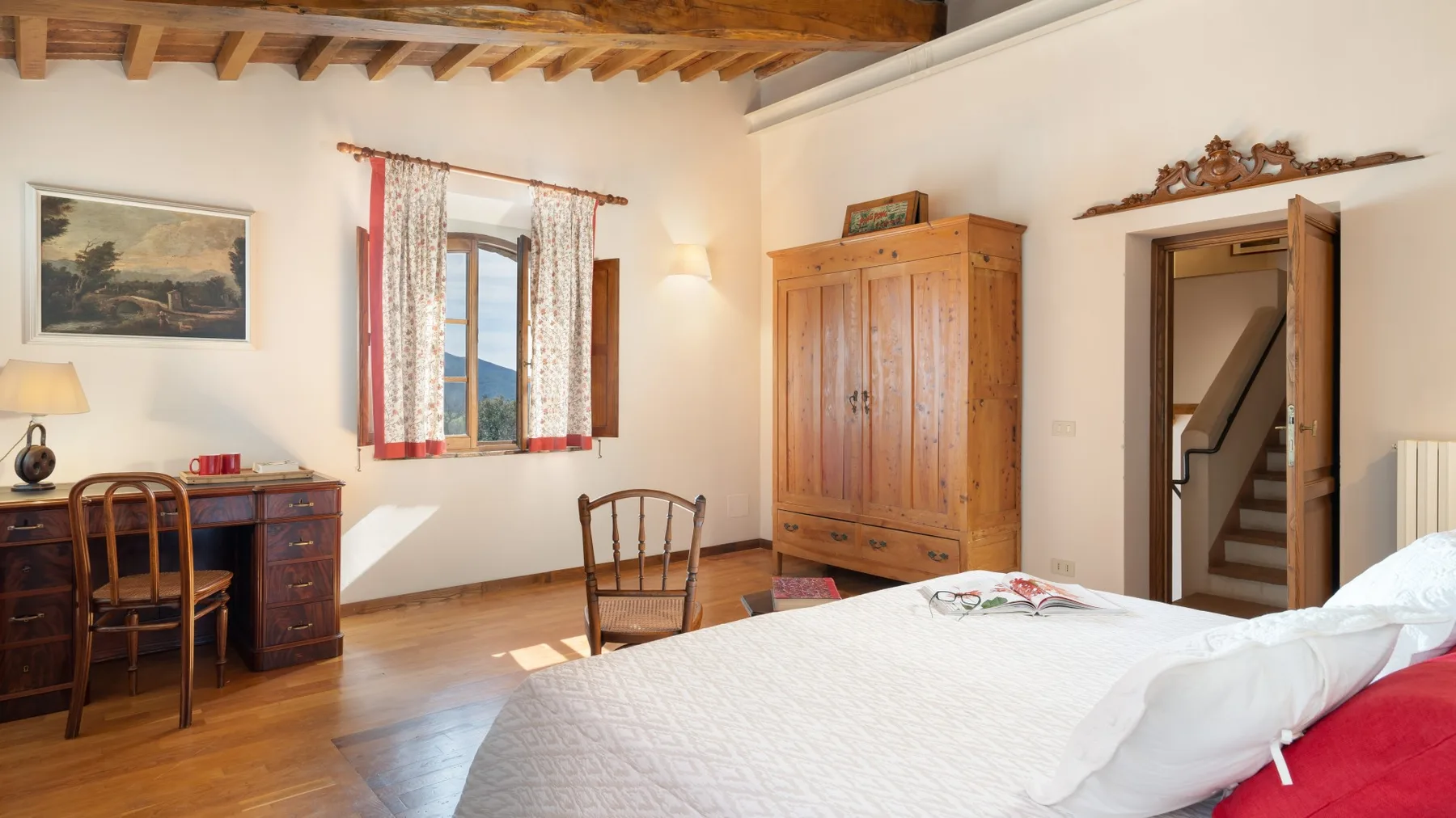 A bedroom with a wooden bed, wardrobe, desk, and a window with curtains.
