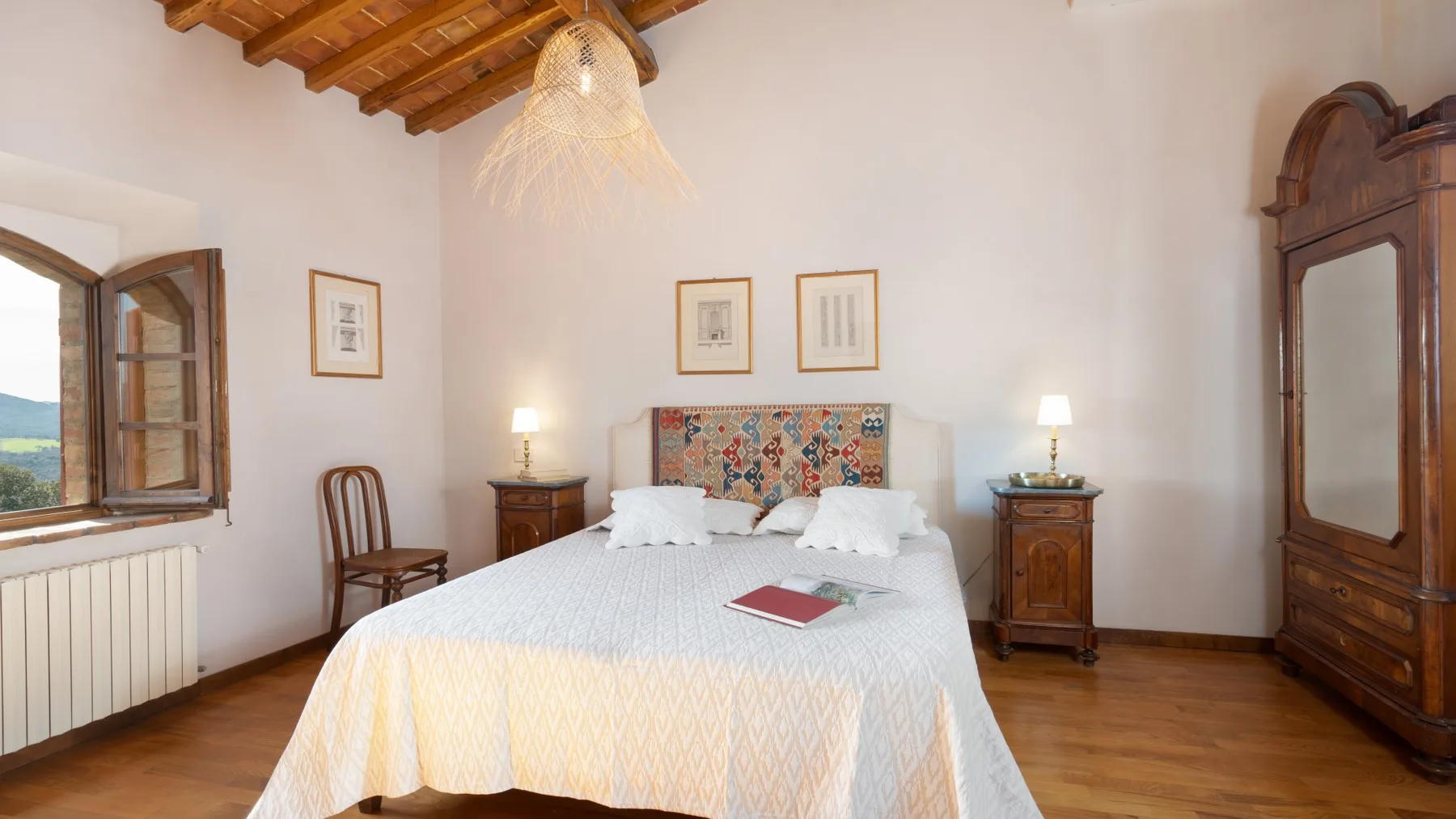 A bedroom with a large bed, wooden furniture, and an open window.