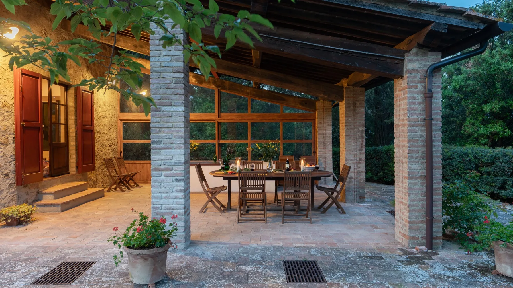 A covered outdoor dining area with a wooden table and seating.
