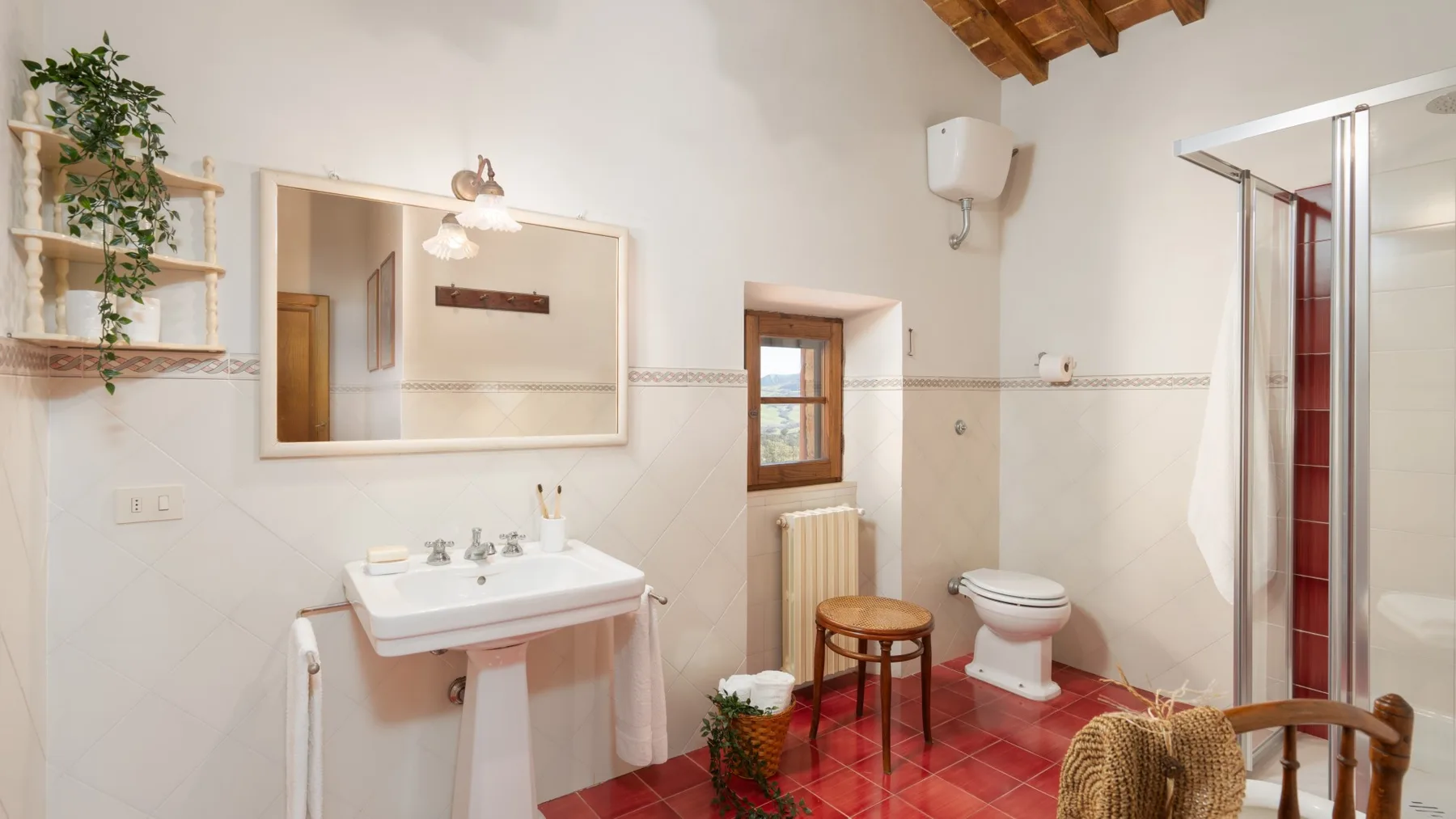 A bathroom with a pedestal sink, toilet, and glass shower enclosure.