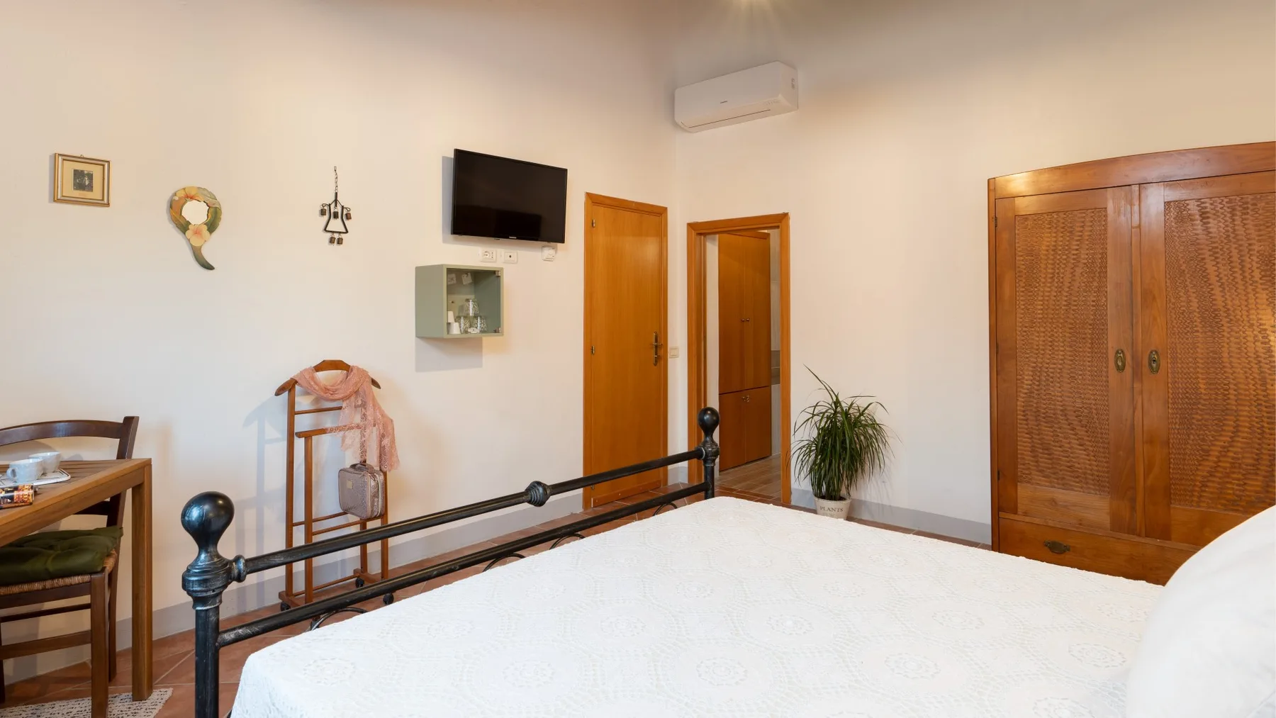 Bedroom with a bed, wooden wardrobes, and a television mounted on the wall.