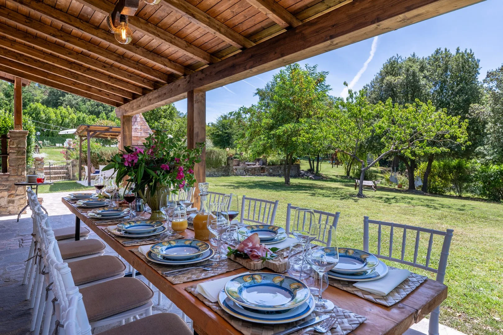 A covered outdoor dining area overlooks a green garden.
