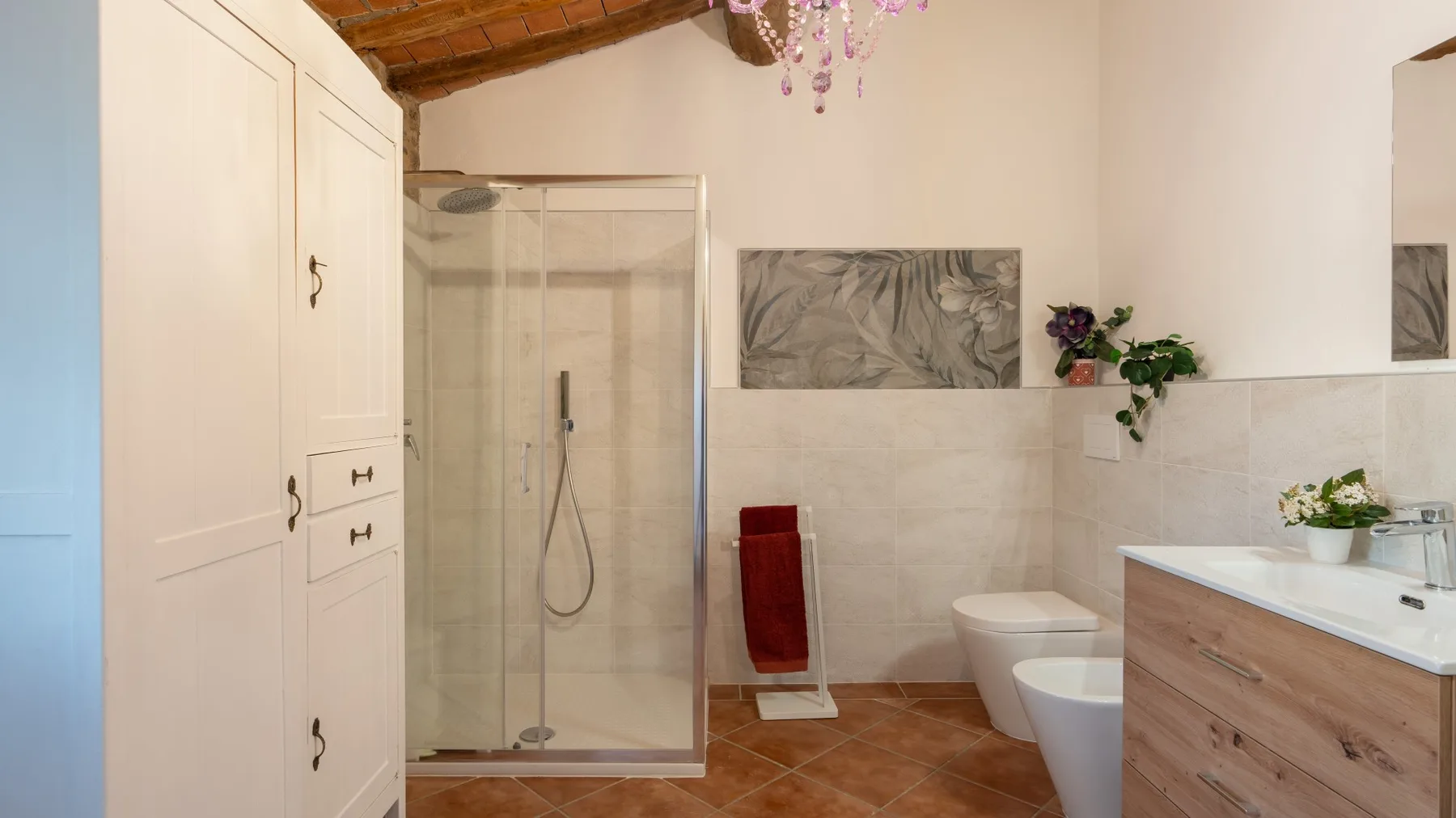 A bathroom with a glass shower, toilet, and wood-front vanity.